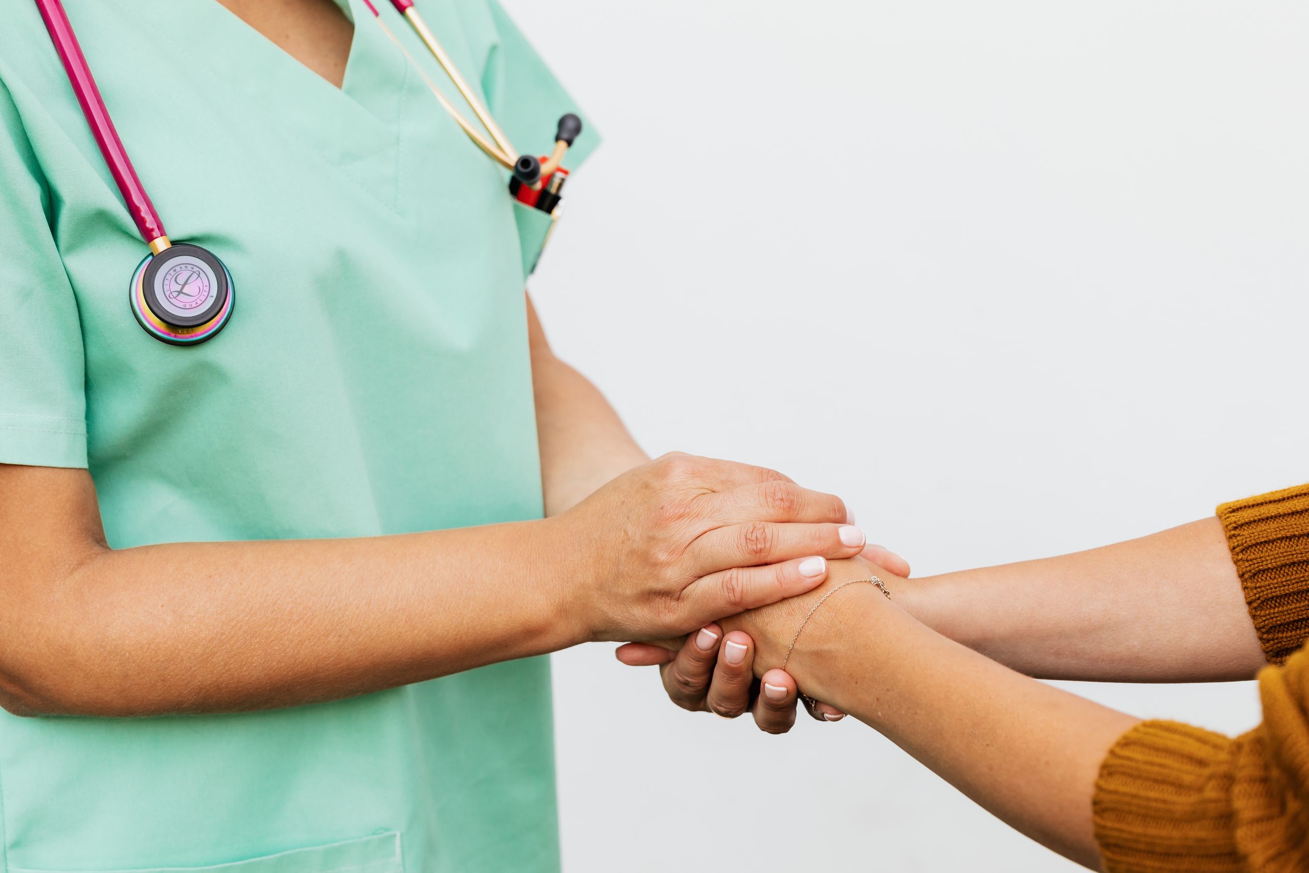 Provider holding a patient’s hands in a gesture of support during a primary care visit